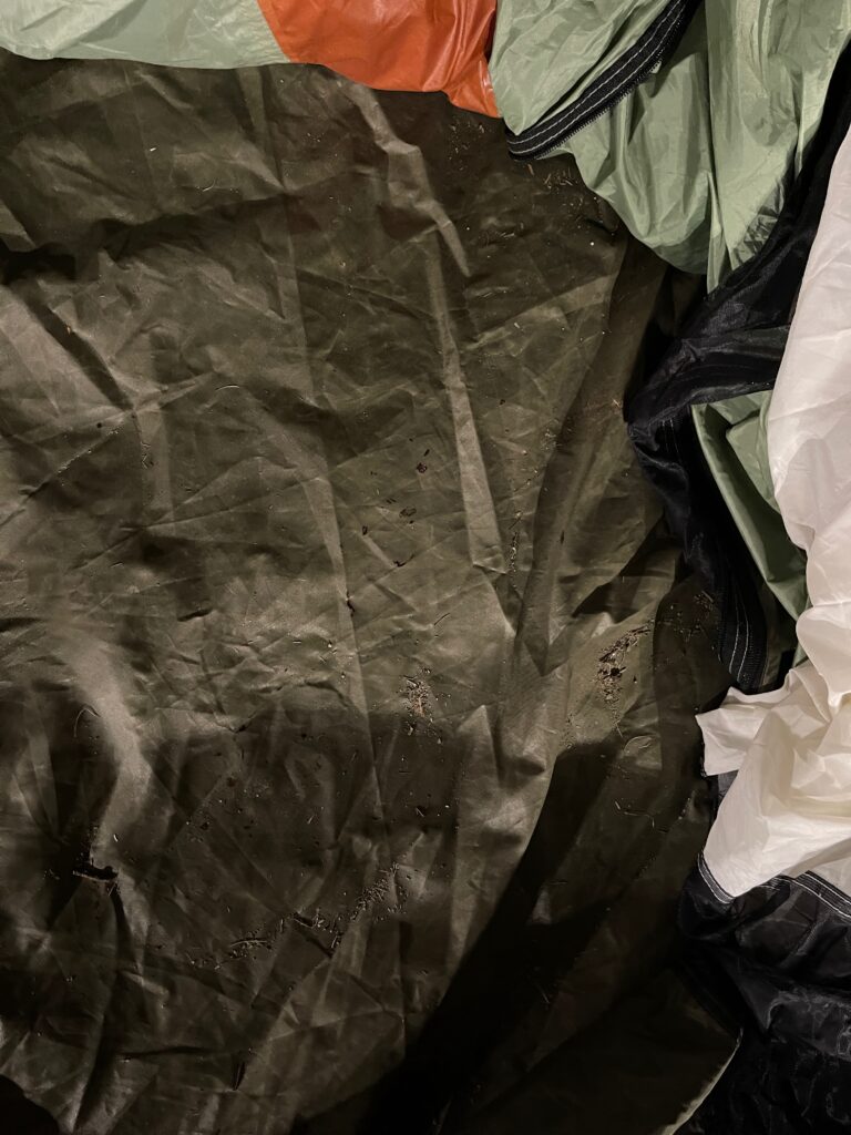 Interior view of a dark green tent floor showing scattered reddish-brown blood-like drops that appeared in the center during a few-hour absence.