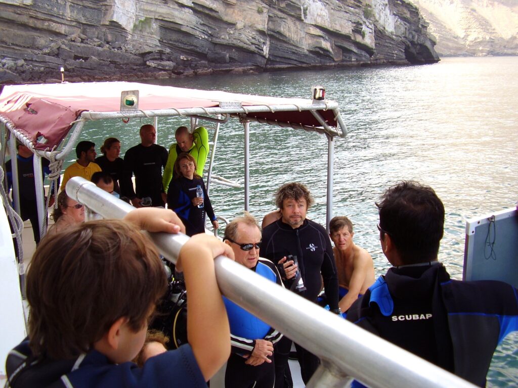 Author Matthew Heines sitting with a group of divers on a boat off the coast of Oman in the Strait of Hormuz.
